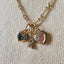 Gold necklace with heart-shaped gemstone pendants on a textured beige background