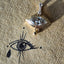 A product picture of a marquise diamond eye pendant. This pendant is made of solid gold, bezel set with two layers with ray pattern on the inner most layer. This pendant also has a four diamond bail and a gold tear drop. Real photo.
