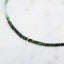 A emerald necklace with an ombre look, created with different shaded green and gold bead spacing.