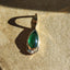 Solid gold green pear shaped tsavorite gemstone pendant with three baguette diamonds set at the bottom.
