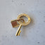 A solid gold push lock connector that is shaped like a key. With the lock positioned at the top ring part of the key with pave diamond set around the ring.