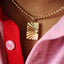 Gold necklace with a rectangular pendant on a red fabric background