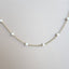 A pearl station necklace with fresh water pearls stationed with rolo link chain segments in between. Small pearls