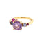 A colored gemstone cluster ring with a pink and purple color palate. Made with different hues and sizes of round colored gemstones set on a gold band.
