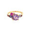 A colored gemstone cluster ring with a pink and purple color palate. Made with different hues and sizes of round colored gemstones set on a gold band.