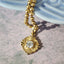 A French style framed accent pendant with a round diamond center. Floral inspired designs in yellow gold.