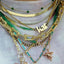 A solid gold station necklace with beaded gemstones evenly spaced out. Styled with other necklaces.
