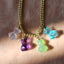 A hand carved teddy bear charm, carved in different gemstones such as rose quartz, green amethyst, purple amethyst, and blue topaz. Finished with a round bail.