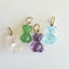A hand carved teddy bear charm, carved in different gemstones such as rose quartz, green amethyst, purple amethyst, and blue topaz. Finished with a round bail.