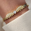 Gold bracelet with diamond accents on a wrist against a neutral background