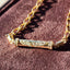 Gold chain with a decorative clasp on a textured purple surface