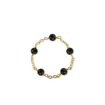 Gold bracelet with black beads on a white background