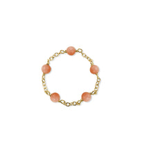 Gold bracelet with pink beads on a white background