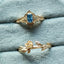 Two gold rings with gemstones on a light blue cushion