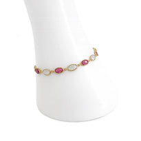 Gold bracelet with pink and white stones on a white stand