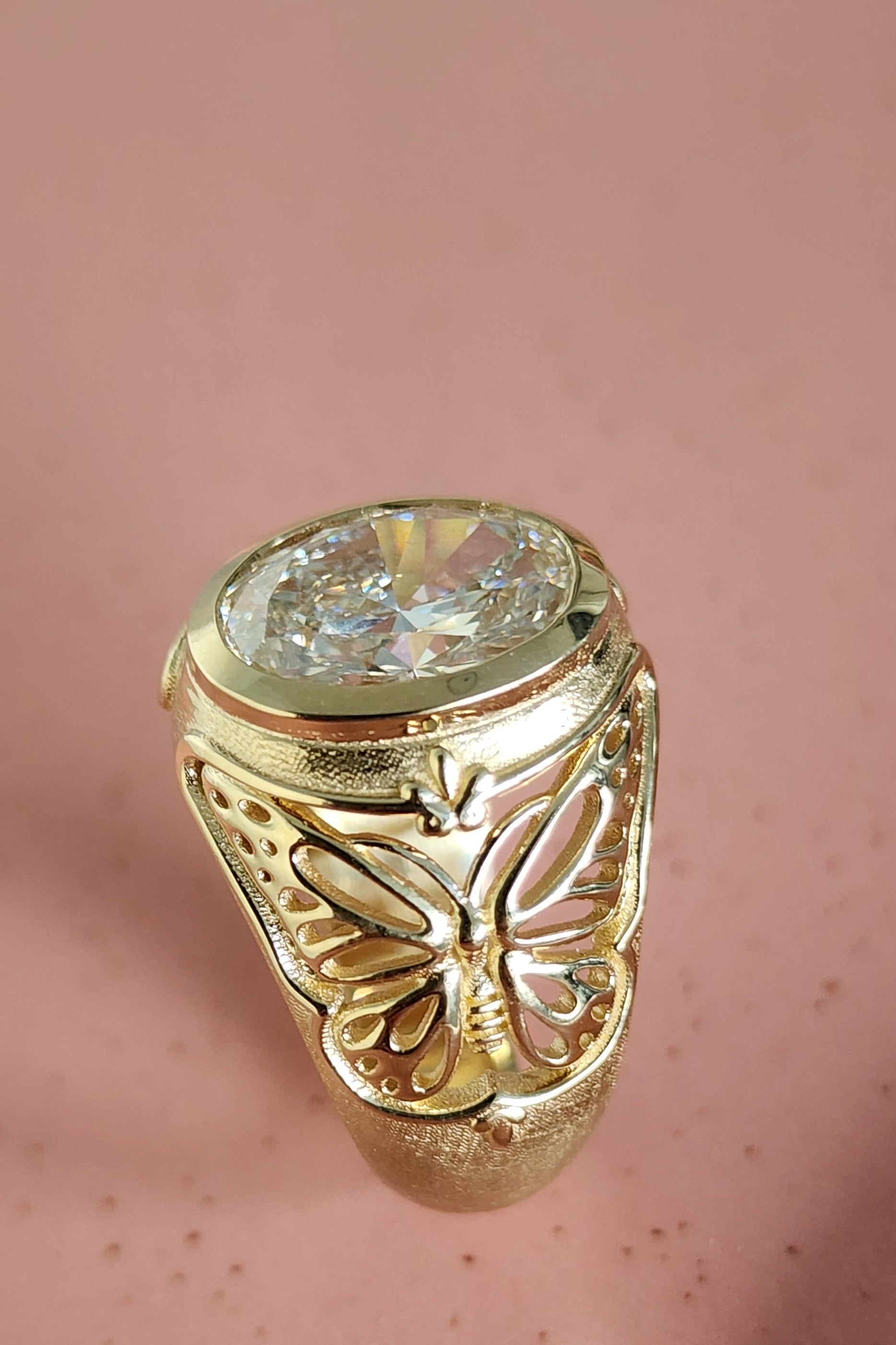Gold ring with a large diamond on a pink background
