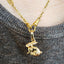 Gold necklace with a pendant on a textured gray fabric background