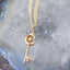 Gold necklace with a key-shaped pendant on a geode background