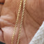 Gold chain necklace on a textured stone surface