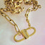 Gold chain necklace with a clasp on a light pink background