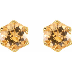 Hexagonal gold earrings with orange gemstones on a white background