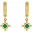 Gold earrings with green gemstones on a white background