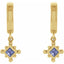 Gold earrings with purple gemstones on a white background