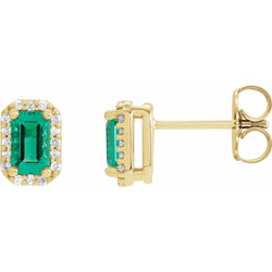 Gold earrings with emerald green gemstones on a white background