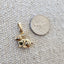 Gold charm next to a quarter on a textured surface