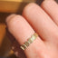 Gold ring with shell design on a finger against a blurred background