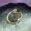 Gold ring with intricate design on a textured surface