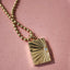 A gold book locket with a diamond on the right hand center at the opening. Finished with ray designs and jump ring bail. 