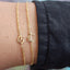 Gold bracelet with anchor design on a wrist against a blurred background