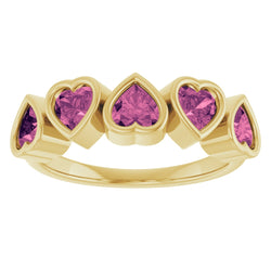Gold ring with heart-shaped pink gemstones on a white background