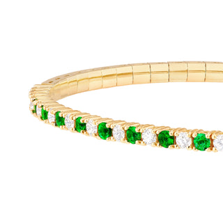 A diamond and emerald alternate stone design bangle. This bangle has gold flex technology and can easily be put onto the wrist. Finished with a secure clasp. 