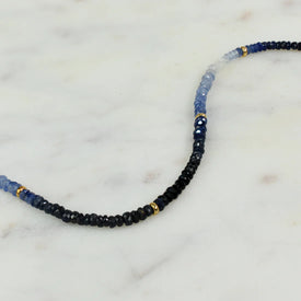 A sapphire necklace with an ombre look, created with different shaded green and gold bead spacing. 