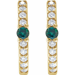 Gold earrings with green gemstones and clear stones on a white background