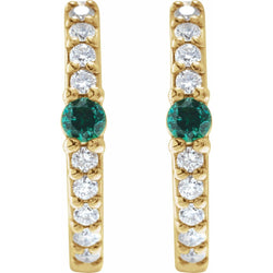 Gold earrings with green gemstones and clear stones on a white background