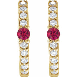 Gold earrings with red gemstones and clear stones on a white background