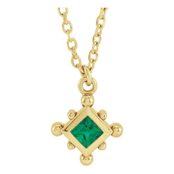 Gold necklace with a green gemstone pendant on a white background