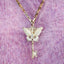 Gold key-shaped pendant with butterfly design on a gold chain against a purple textured background