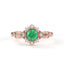 Rose gold ring with a green gemstone and diamond accents on a white background