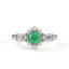 Ring with a green gemstone and diamond-studded band on a white background