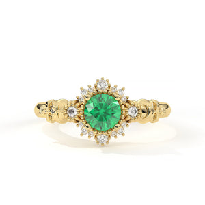 Gold ring with a green gemstone and diamond accents on a white background
