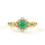 Gold ring with a green gemstone and diamond accents on a white background