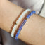 Close-up of a wrist wearing two beaded bracelets on a neutral background