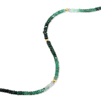 A faceted gemstone ombre beaded bracelet with three gold accents and a round clasp. 