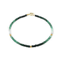 A faceted gemstone ombre beaded bracelet with three gold accents and a round clasp. 