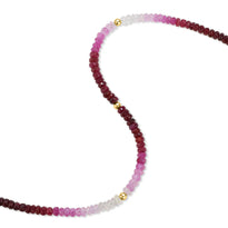 A faceted gemstone ombre beaded bracelet with three gold accents and a round clasp. 