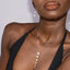 Woman wearing a pearl necklace and earrings against a neutral background